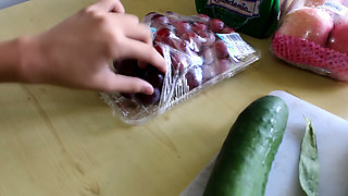 Asian Babe in a Red Corset Plays with a Cucumber on the Kitchen Table